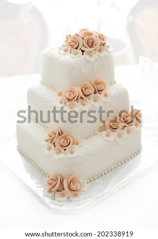 Wedding cake with pink flowers on light background