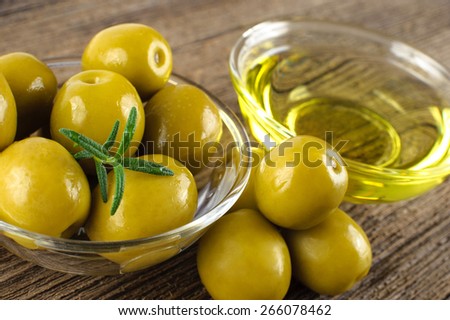 Green marinated olives, olive oil on a wooden table