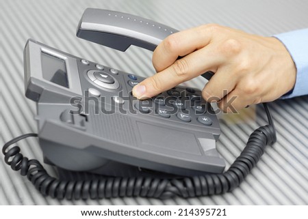 Business man hand is dialing a phone number with picked up headset