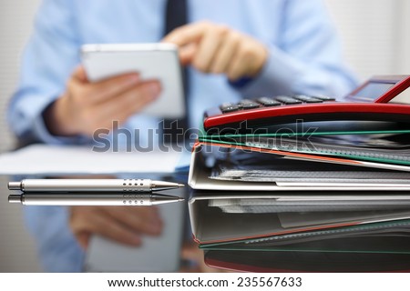 files and folders and businessman in background with tablet pc in hands