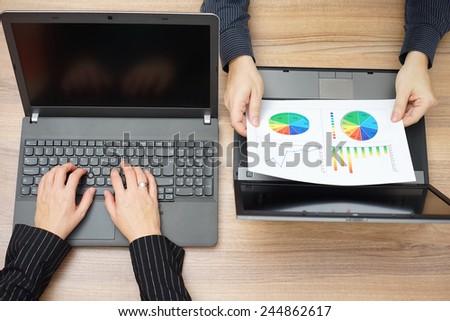 top view of businesswoman typing on computer laptop and businessman analyzing report