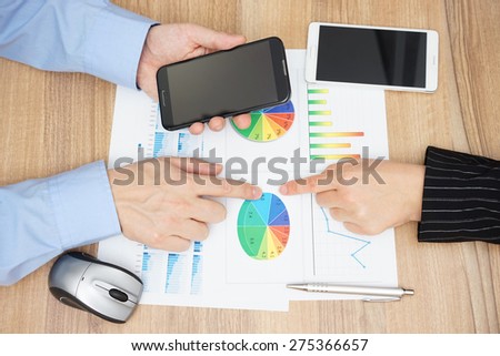top view of business people analyzing sales report and  reading information on mobile phone