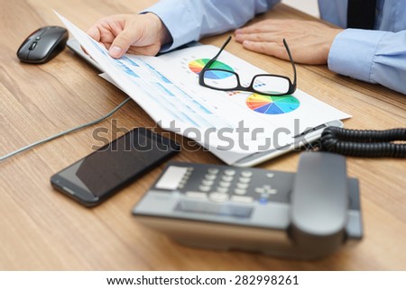 busy businessman analyzing a lot of  graphs and business data at  the desk