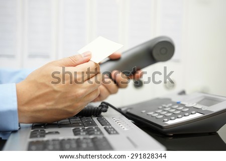 businessman holds business card in his hand  on workplace to contact business client by phone