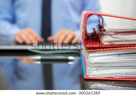 accountant with stack of invoices is inserting data into computer database