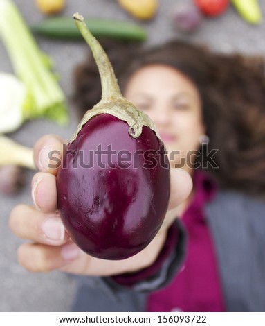 Indian eggplant in forefront with young corporate woman and vegetables in background
