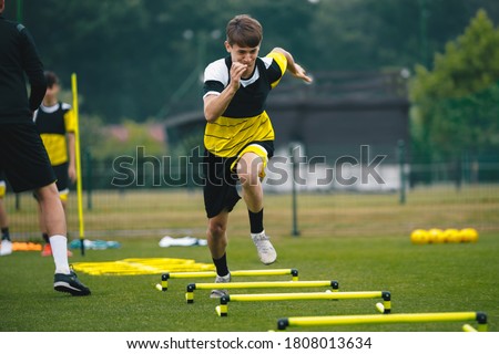 Soccer player running fast and ladder skipping. Teenagers on soccer training camp. Boys practice football witch young coach. Junior level athletes improving soccer skills on outdoor training