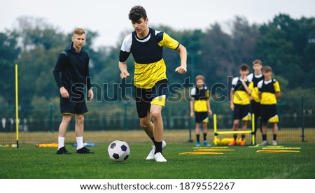 Youth Sports Player Running on Training Field. Junior Football Club Practice Session. Teenagers in Soccer Training Sportswear with Young Coach. Sports Educational Equipment