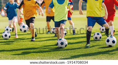 Football soccer children training class. Kids practicing football on grass field. Group of school children running and kicking soccer balls on summer training camp