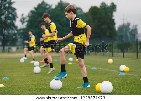Teenage Boys Training Sports in a Row. Soccer Summer Camp for Young Boys. Happy Football Players on Practice Session. Youth Team Kicking Balls on Turf Pitch. Soccer Training Trail With Equipment