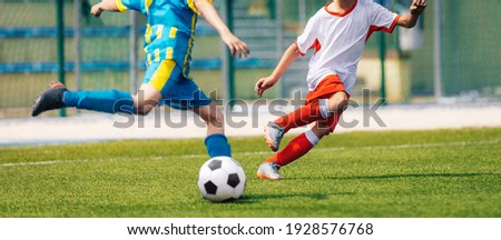 Two Soccer Boys Kicking Ball in Opposite Teams. Football Duel; Kicking Ball Moment. Young Football Players Running in Duel and Playing Soccer Tournament Match. Sports Competition for Youth Athletes