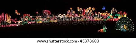 Brightly colored light display of garden flowers, butterflies, and peacock
