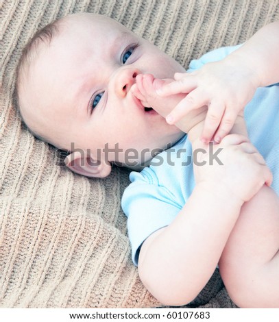 Cute baby boy with foot in his mouth, tasting toes
