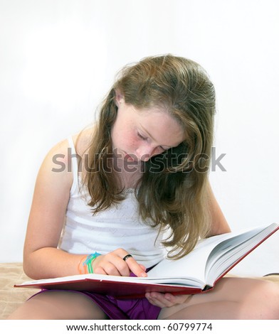 Beautiful young girl reads book using her finger to keep her place