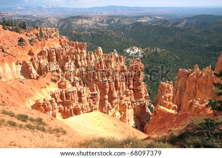 Hiking trails wind through luminous orange sandstone spires, sculpted by wind and water erosion, towering above Bryce canyon's valley floor