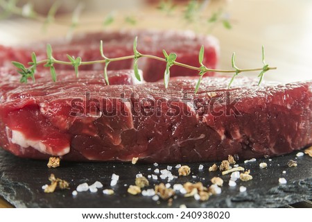 Raw beef tenderloin with spices over a blackboard