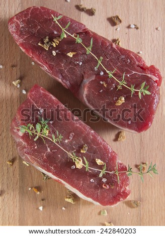 Raw beef tenderloin with spices over a wooden table