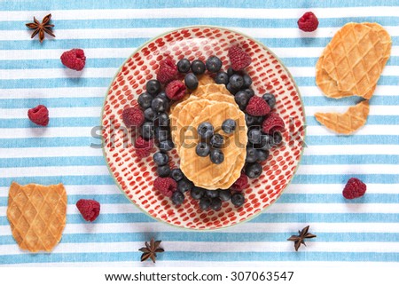 Waffles breakfast with berries, raspberries and blueberries over blue and white background