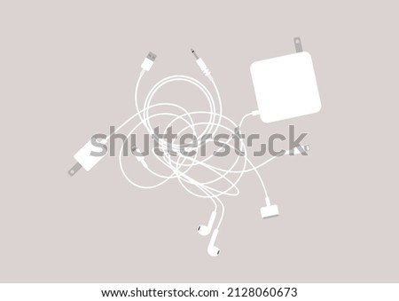 A set of laptop and mobile phone chargers, cables and earphones tangled in a big knot