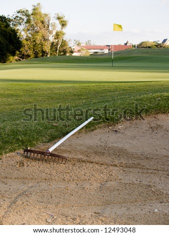 Green Golf Course Series - portrait orientation Sand bunker with rake and putting green with flag in the background