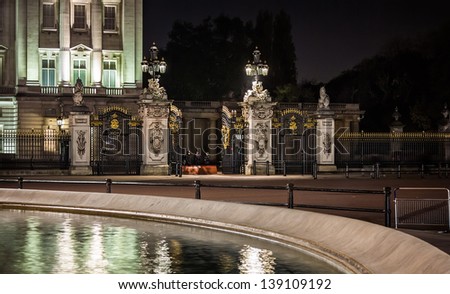 Buckingham Palace\'s illuminated gates guarded by police at night, November 14, 2012. Buckingham Palace is the official London residence of the British monarch.