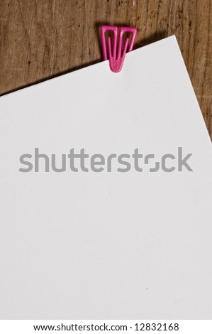 White paper with clip, on wooden surface.