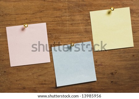 Three Notes with Tack on wooden board, in three different colors.