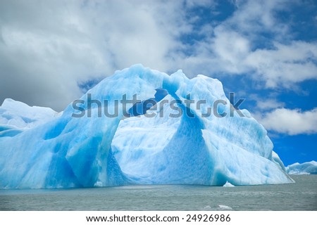 Iceberg floating in the water forming an arch.