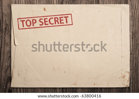 Open yellow envelope with top secret stamp and papers, on wooden table, clipping path.