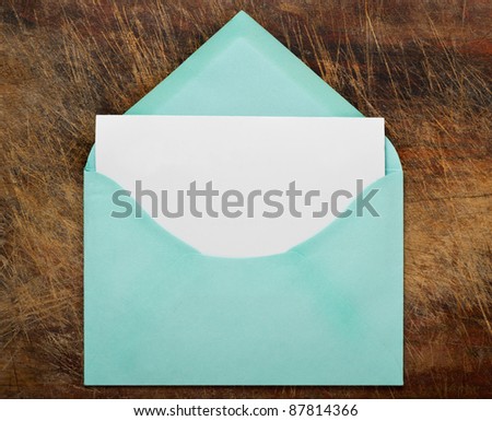 Vintage open envelope with blank paper on wood .