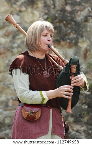 NOGENT LE ROTROU,FRANCE,MAY16 :A woman wearing traditional medieval clothes play a bagpipe during a historical reenactment festival near the Saint Jean Castle on May 16 2010 in Nogent le Rotrou,France