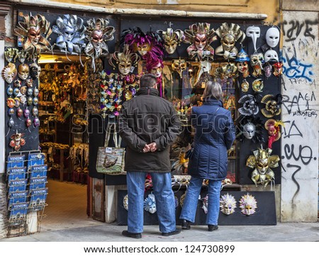 VENICE-FEB 18:Unidentified couple of tourists in front of a shop full of traditional masks and souvenirs on February 18, 2012 in Venice. In 2012 the Venice Carnival was held between 11- 21 February.