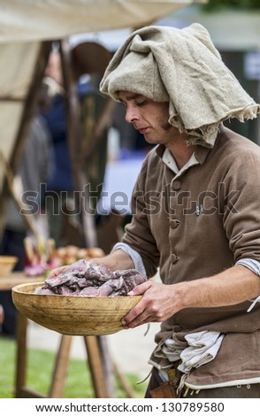 NOGENT LE ROTROU,FRANCE,MAY19 :Medieval man carry a wooden plate with venison for food preparation, during a reenactment festival around the St. Jean Castle on May 19 2012 in Nogent le Rotrou, France.