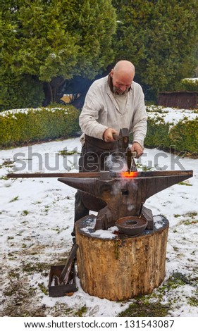 RODEMACK,FRANCE-DEC 09:Unidentified  blacksmith hammering a piece of hot red fire outside in winter during a historical  reenactment festival on December 9,2012 in Rodemack in France.