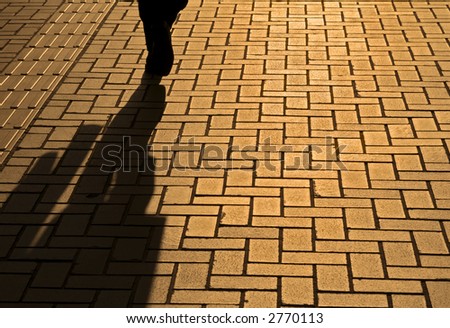 Sunset pavement reflections of a walking businessman