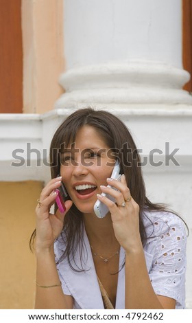 A young woman getting good new on two mobile phones in the same time.