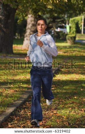 Young woman running in an autumn park.