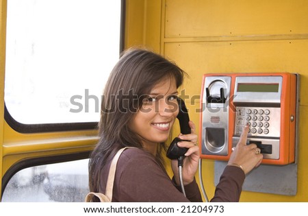 Image of a beautiful young smiling woman in a public phone cabin.