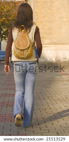 College girl with backpack walking near the university building.