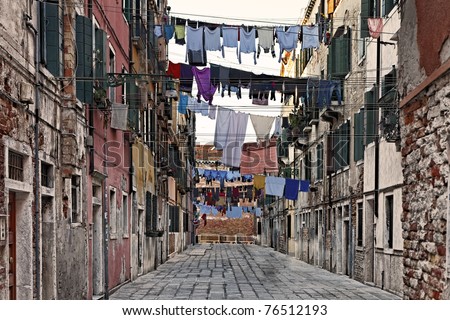 Traditional Italian street with clothes hanging out to dry between old houses, somewhere in Venice.
