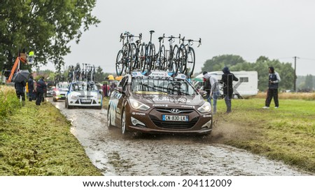ENNEVELIN, FRANCE - JUL 09:Row of technical cars driving on a cobbled road during the stage 5 of Le Tour de France in Ennevelin on July 09 2014.