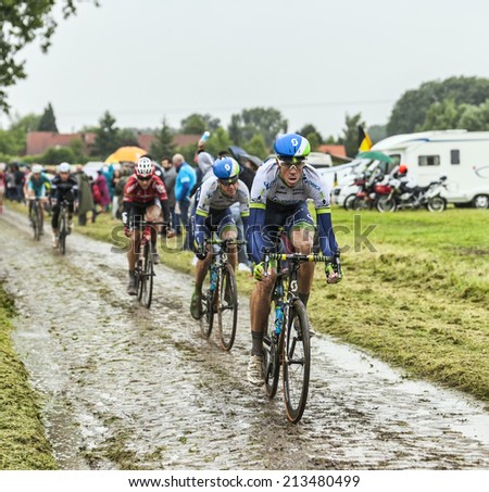 ENNEVELIN, FRANCE - JUL 09:A group of cyclists led by the cyclist Mathew Hayman (Orica GreenEDGE) riding on a cobbled road during the stage 5 of Le Tour de France in Ennevelin on July 09 2014