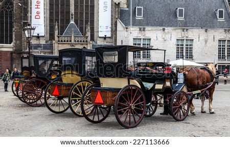 AMSTERDAM, OCT 30: Unidentified tourists and a row of carriages parked in Dam Square on October 30, 2011 in Amsterdam - one of the most popular tourist destinations in Europe