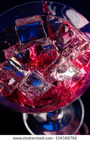 Martini glass with ice cubes and red drink