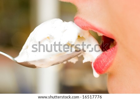 Close-up of pretty woman red lips with ice-cream in the spoon