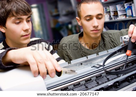 Two young technicians repairing printer
