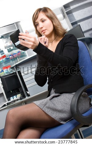 Voluptuous young business lady applying cosmetics at workplace