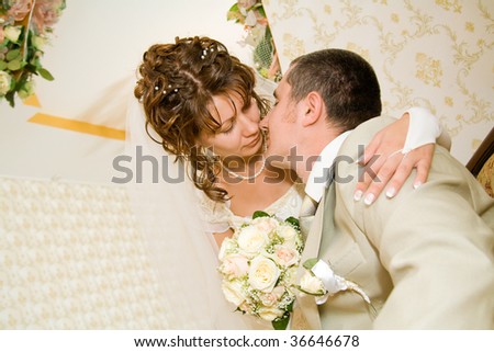 Beautiful young bride kissing groom in decorated indoor setting