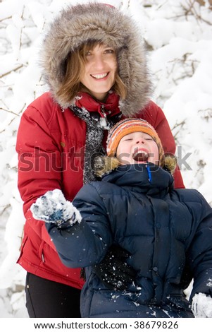 Mother playing with son in winter forest