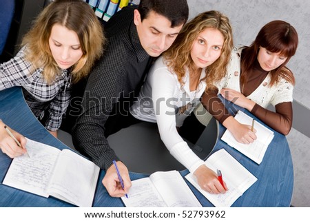 Team of young colleagues taking notes on corporate meeting